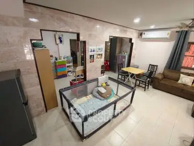 Spacious living room with playpen, dining area, and air conditioning, perfect for family living.