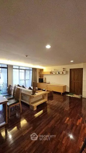 Spacious living room with wooden flooring and modern furniture in a cozy apartment.