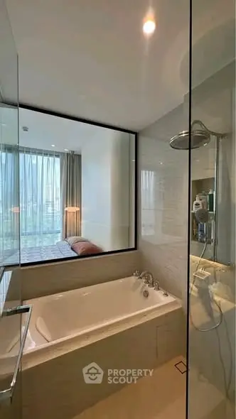 Modern bathroom with glass shower and bathtub, featuring a window view into a stylish bedroom.