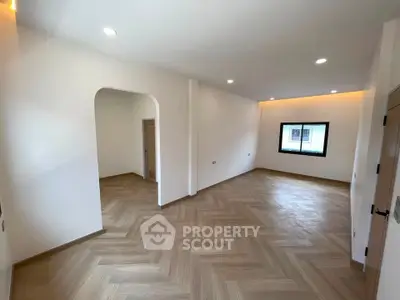 Spacious modern living room with elegant herringbone wood flooring and ambient lighting.