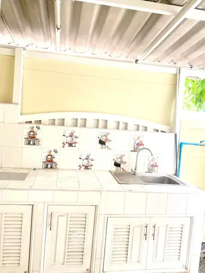 Charming outdoor kitchen with tiled backsplash and stainless steel sink, perfect for entertaining.