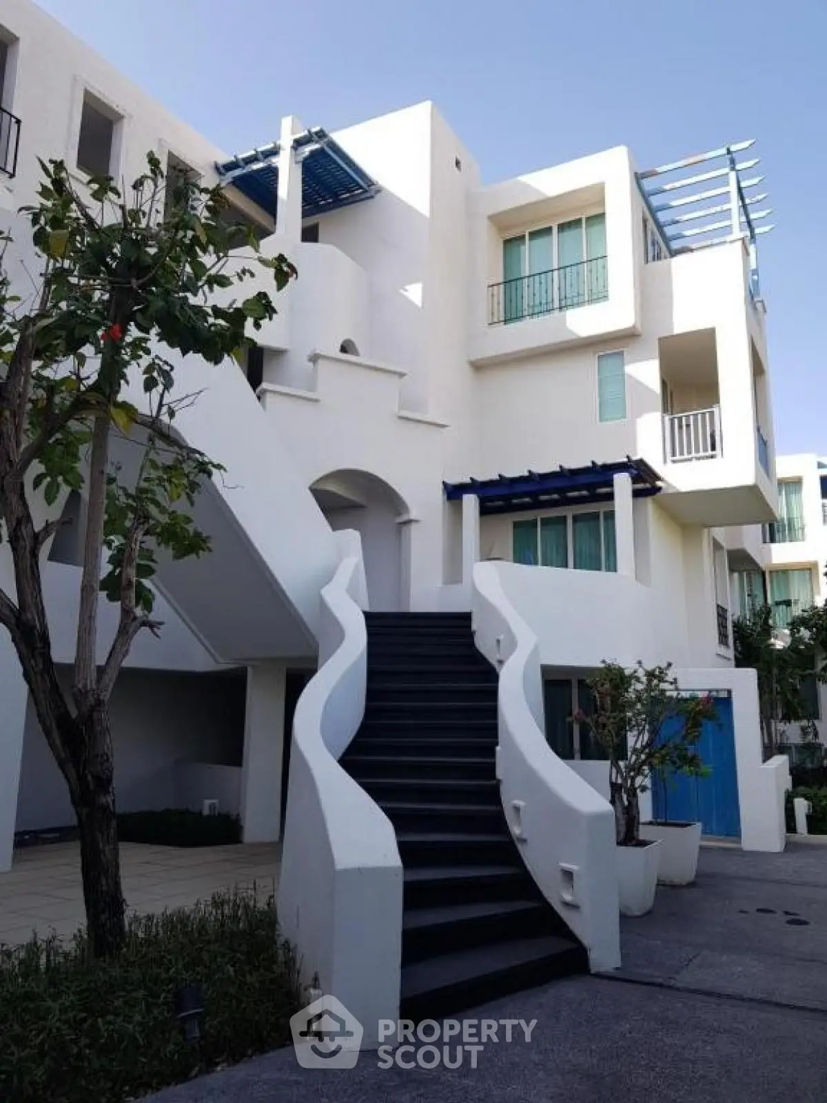 Modern white building with unique staircase and lush greenery