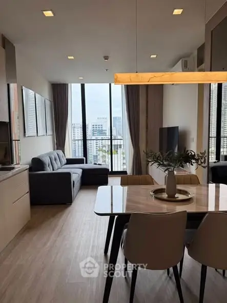 Modern living room with city view, stylish furniture, and elegant dining area in a high-rise apartment.