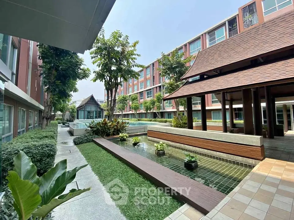 Modern apartment complex with lush garden and water feature, perfect for serene living.