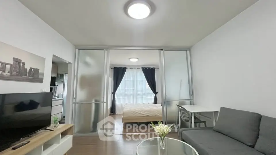Modern studio apartment with glass partition, cozy living area, and natural light.