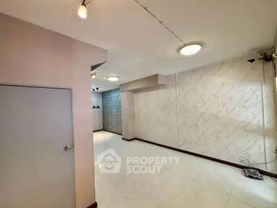Spacious interior with modern lighting and marble accent wall, ideal for versatile living space.