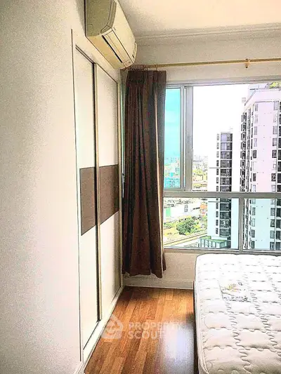 Bright bedroom with city view, featuring wooden flooring and air conditioning, perfect for urban living.