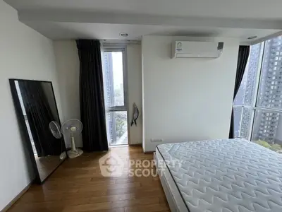 Modern bedroom with large window and city view, featuring hardwood floors and air conditioning.