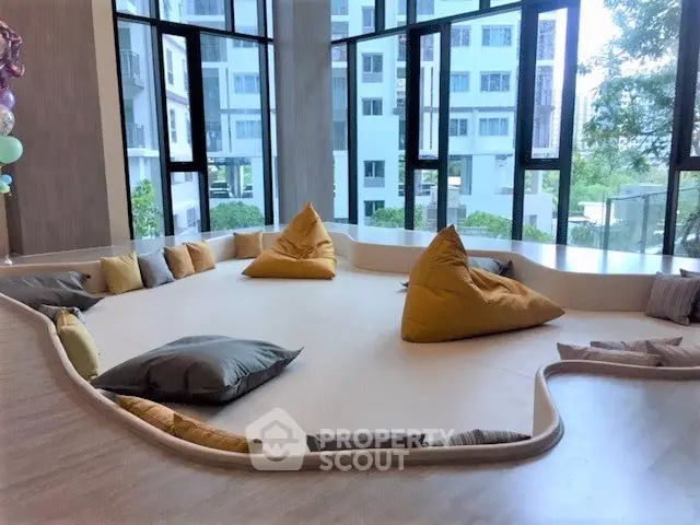 Modern communal lounge with large windows and cozy seating in a contemporary building.