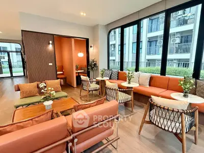 Modern living room with stylish furniture and large windows in a contemporary apartment building.