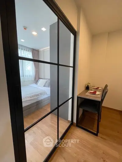 Modern apartment with cozy bedroom and dining area, featuring sleek sliding glass doors and elegant decor.