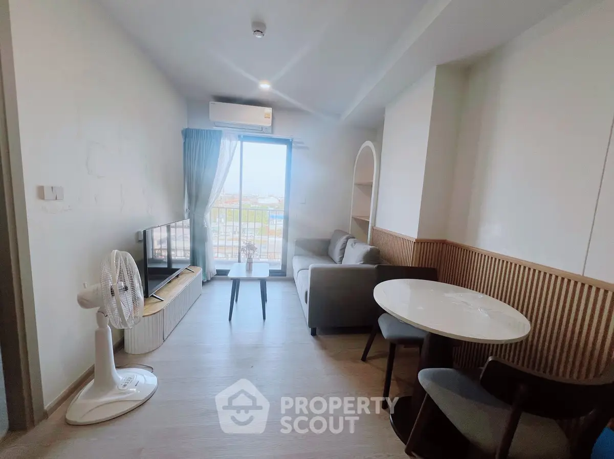 Modern living room with balcony view, featuring stylish furniture and natural light.