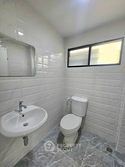 Modern bathroom with sleek white tiles and contemporary fixtures.