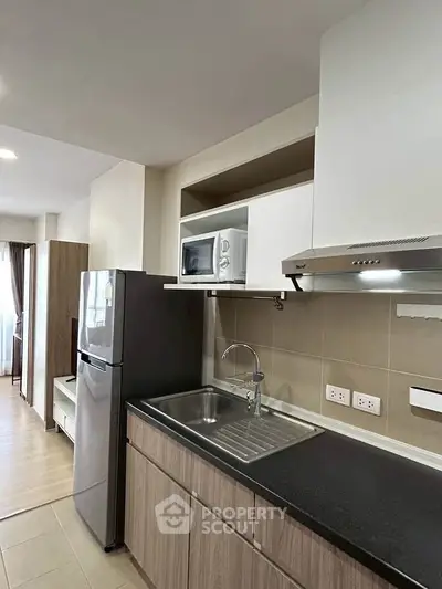 Modern kitchen with sleek cabinetry, stainless steel sink, and built-in microwave in a stylish apartment.