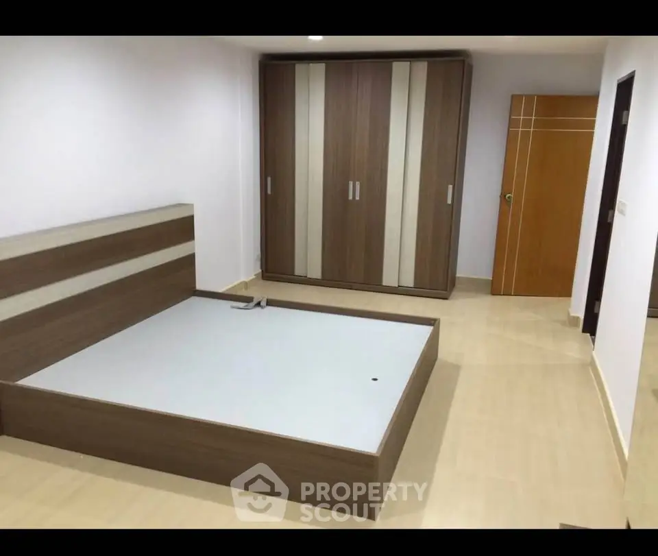 Spacious bedroom with modern wooden furniture and ample storage space.