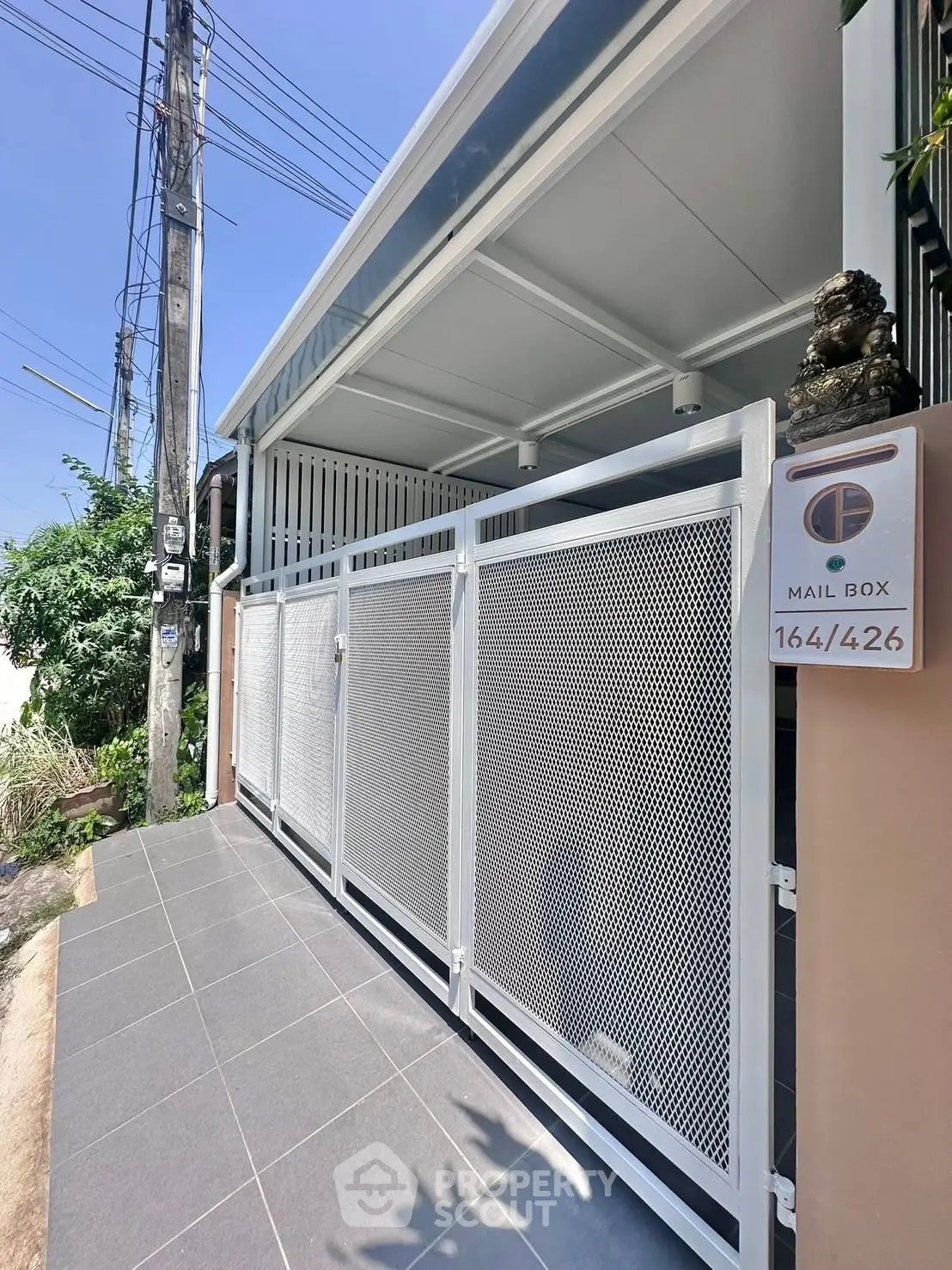 Modern gated entrance with sleek mailbox and tiled pathway in a contemporary residential setting.