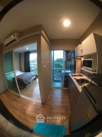 Modern compact apartment with kitchen and bedroom, featuring sleek design and natural light.