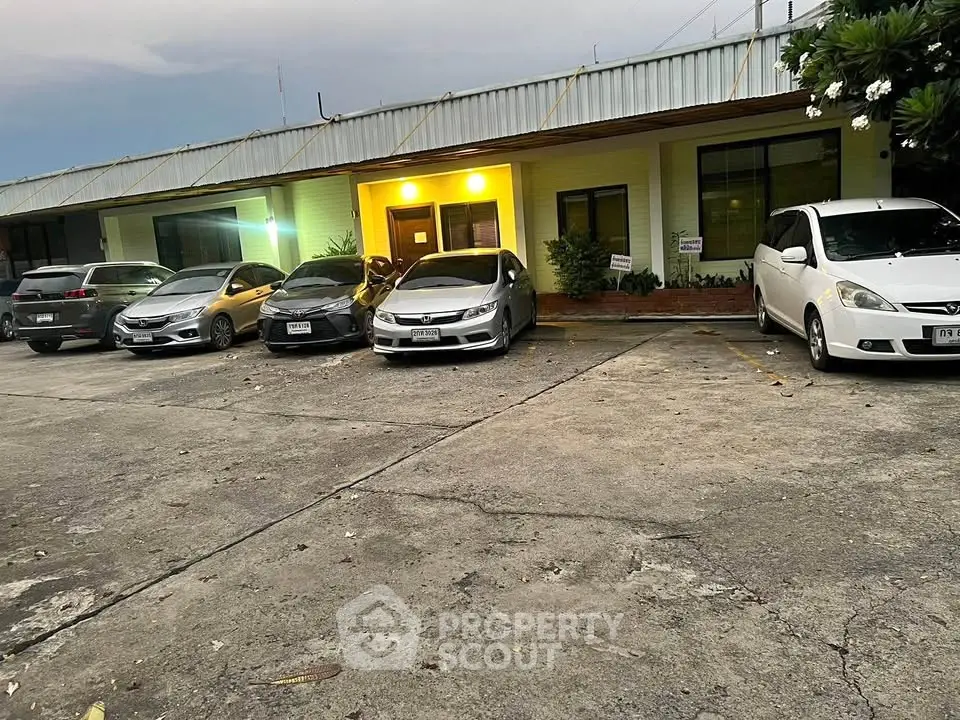 Spacious parking area in front of a commercial building with multiple cars parked.