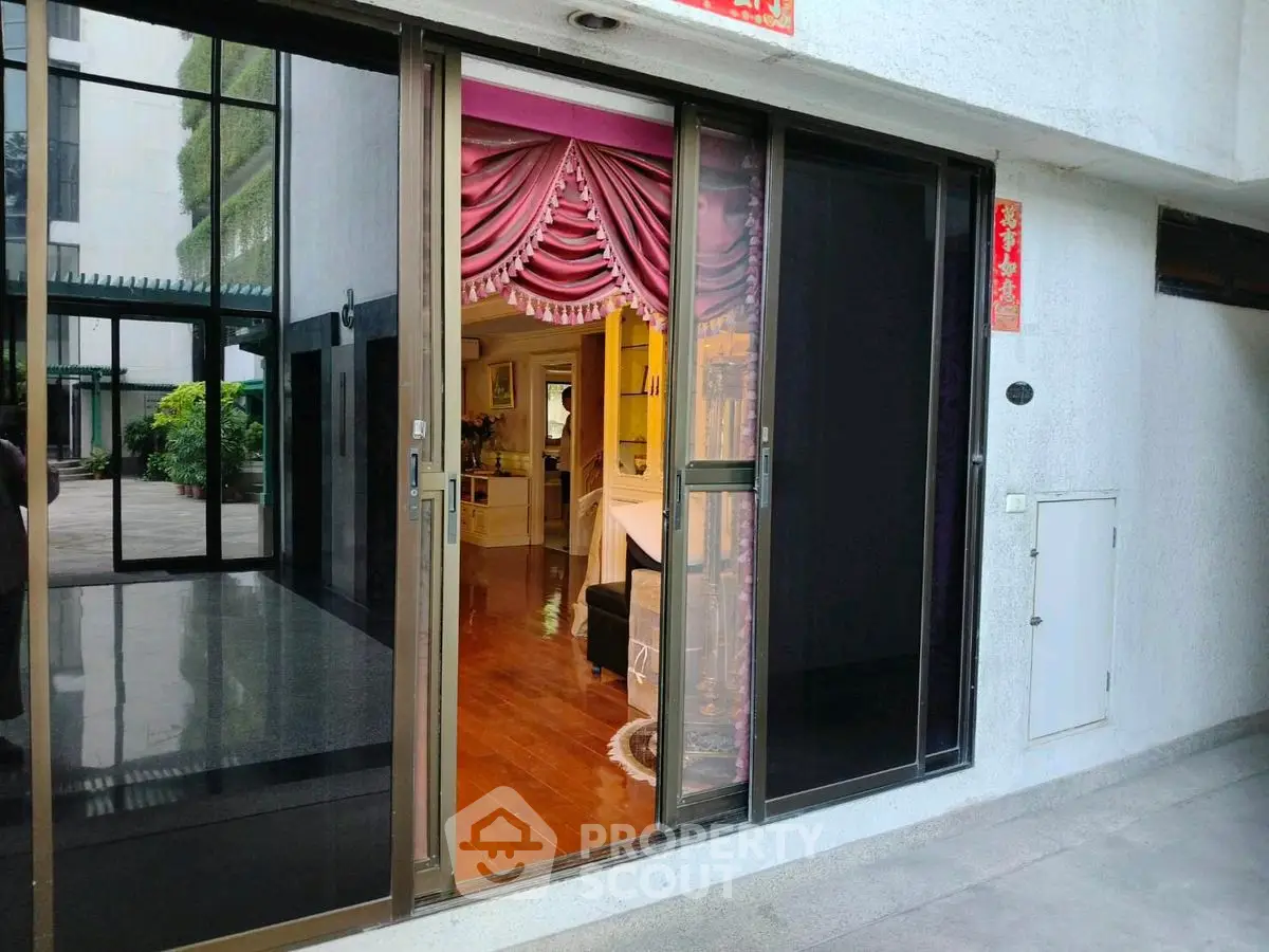 Elegant interior view through sliding glass doors with luxurious drapery and polished wooden floors.