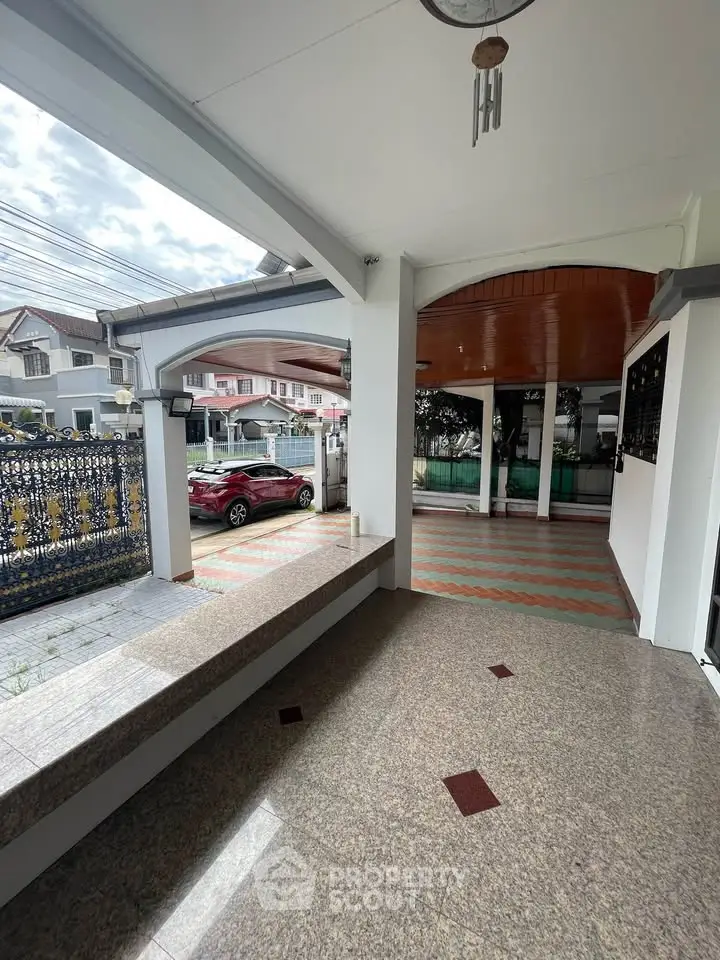 Spacious covered outdoor area with tiled flooring and elegant archways in a residential property.