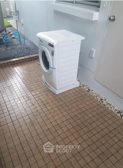 Outdoor laundry area with washing machine on tiled floor