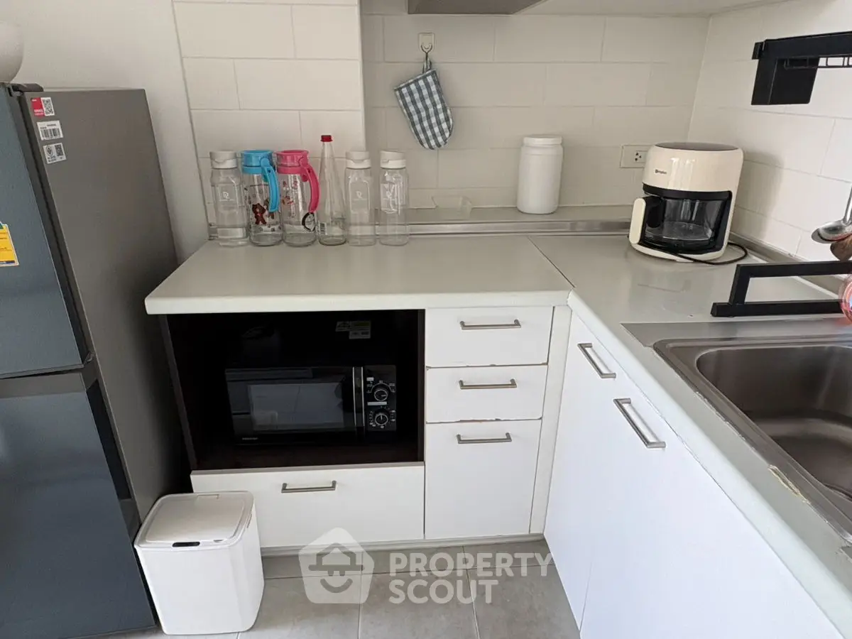 Modern kitchen with sleek white cabinets, microwave, and coffee maker