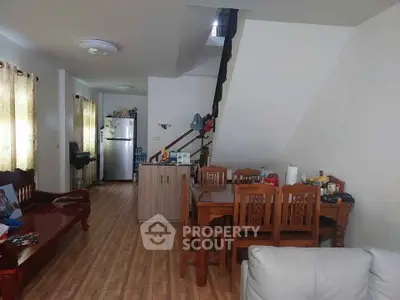 Spacious living and dining area with wooden furniture and modern kitchen appliances.