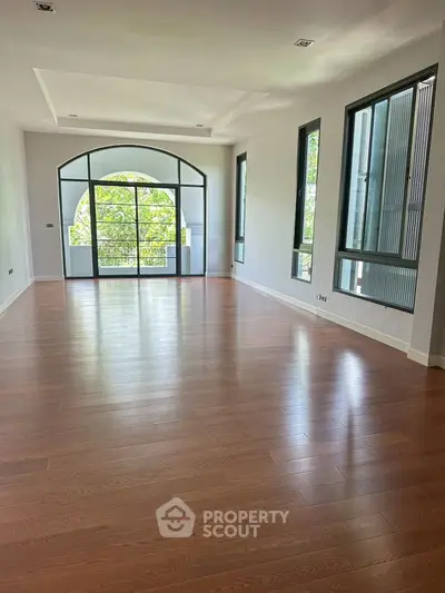 Spacious living room with large windows and hardwood floors, perfect for natural light and modern living.