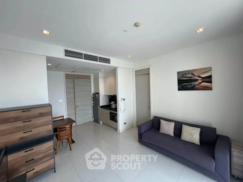 Modern living room with sleek furniture and open kitchen layout in a stylish apartment.
