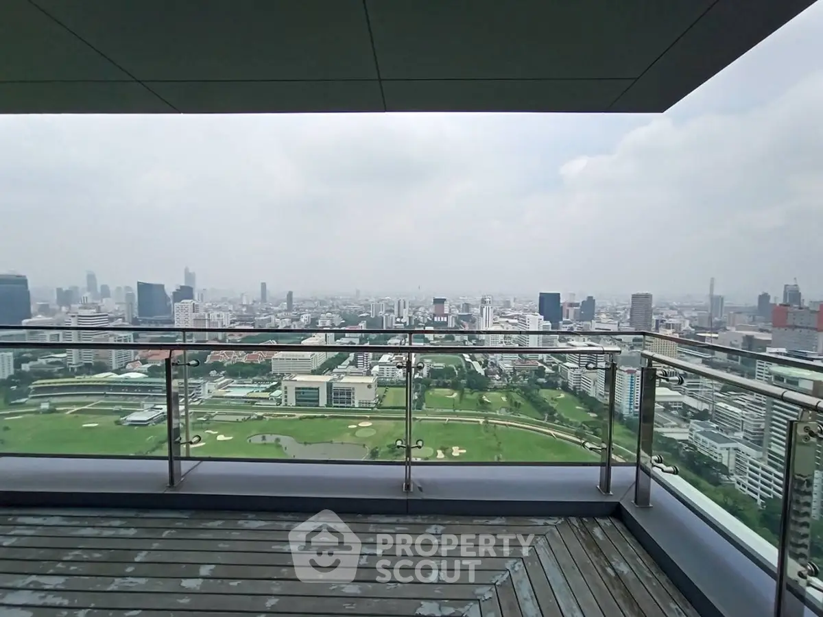 Stunning cityscape view from a high-rise balcony with glass railing and wooden deck.