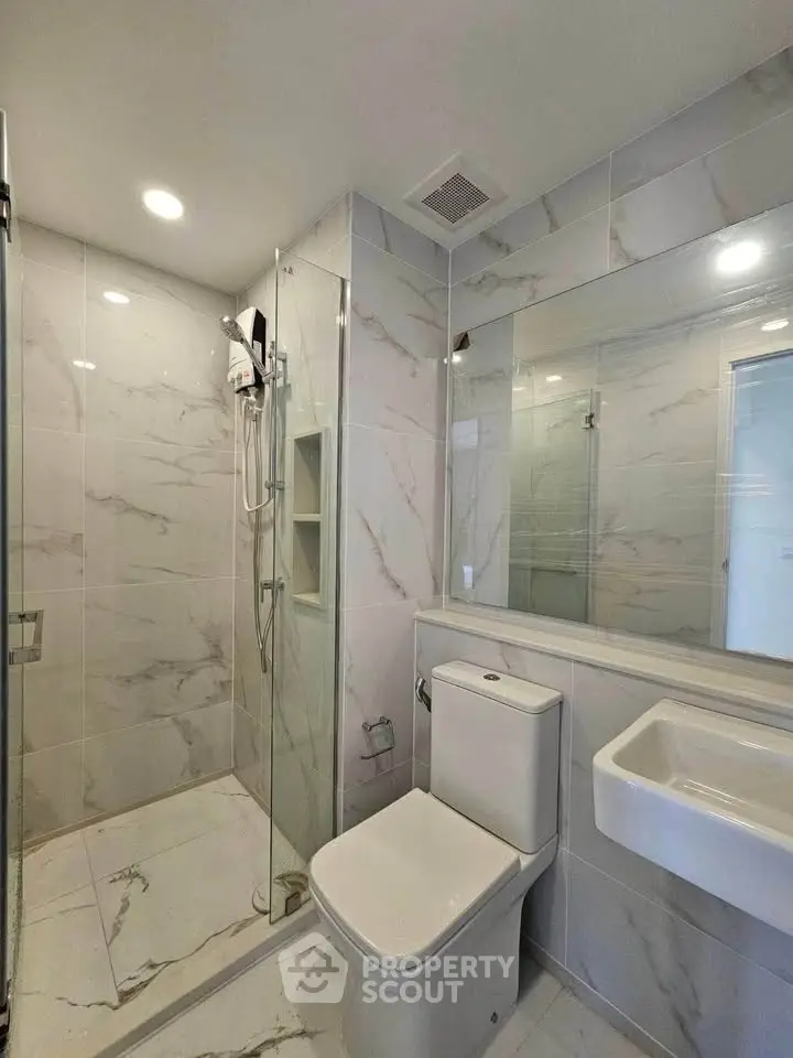 Modern bathroom with sleek design, featuring glass shower and elegant marble tiles.
