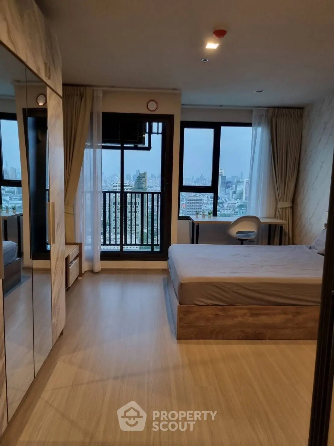 Modern bedroom with city view and large mirrored wardrobe