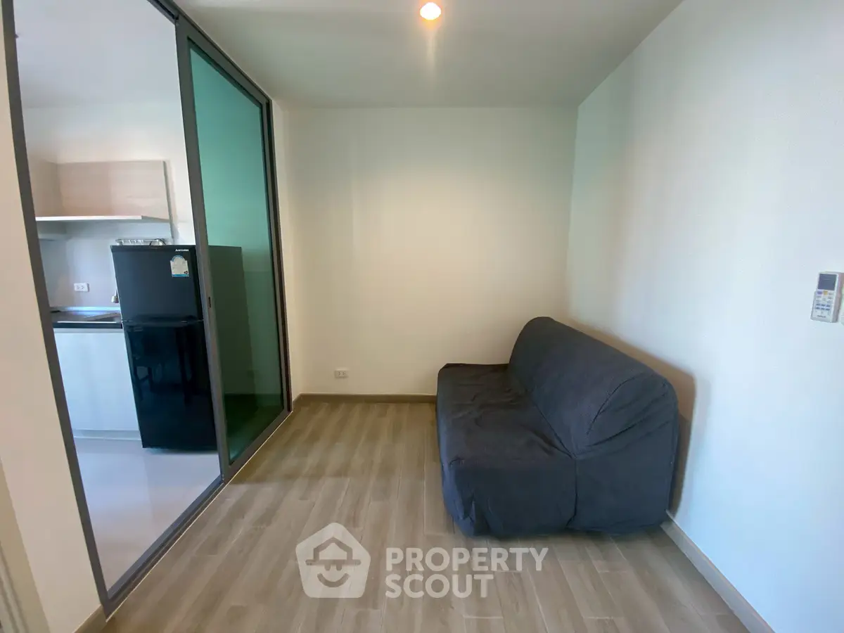 Modern living room with sleek design and sliding glass door to kitchen area.