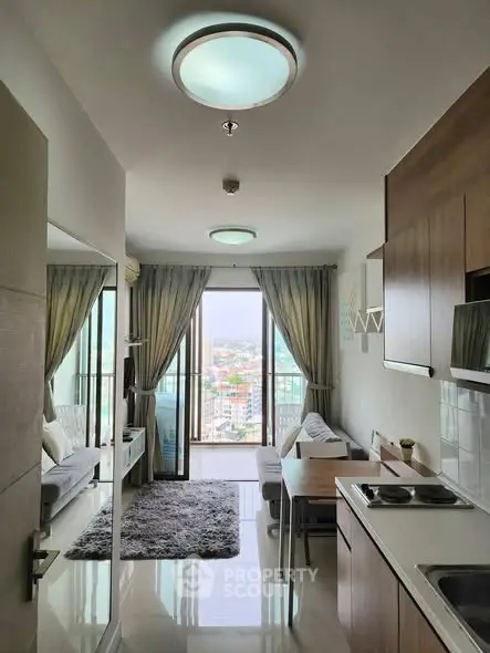 Modern apartment interior with open kitchen and living room, featuring large windows and city view.