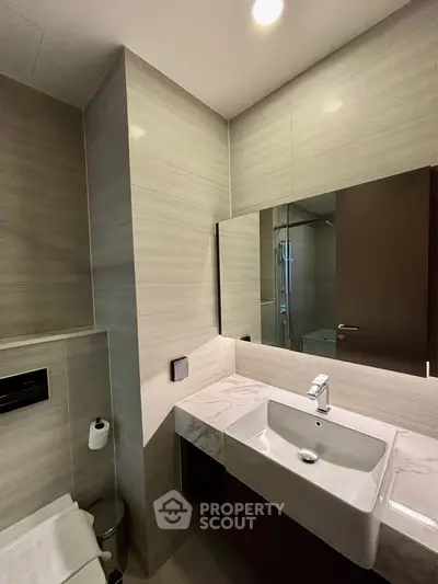 Modern bathroom with sleek design and elegant fixtures, featuring a large mirror and stylish sink.