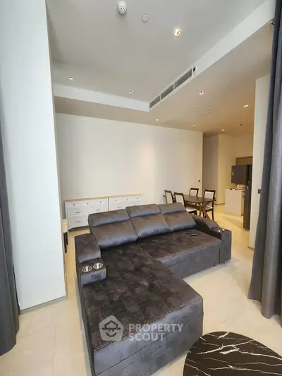 Spacious modern living room with stylish gray sectional sofa and elegant dining area in open layout.
