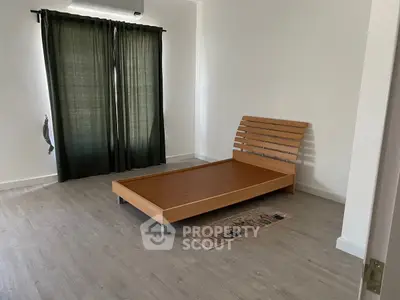 Minimalist bedroom with wooden bed frame and dark curtains