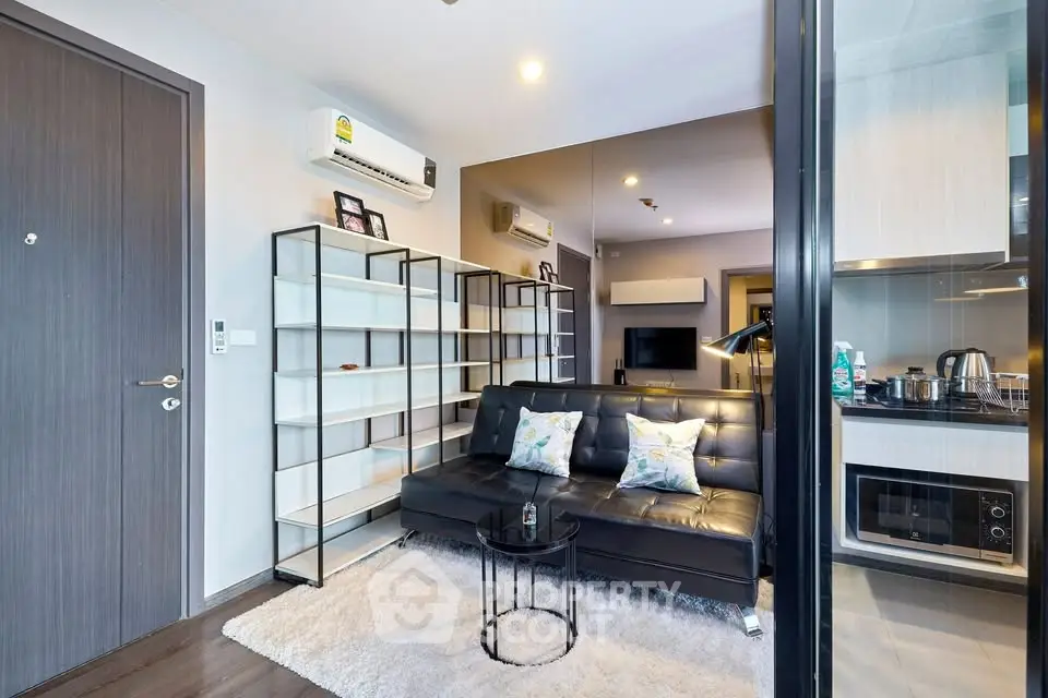 Modern living room with sleek black sofa and open kitchen layout
