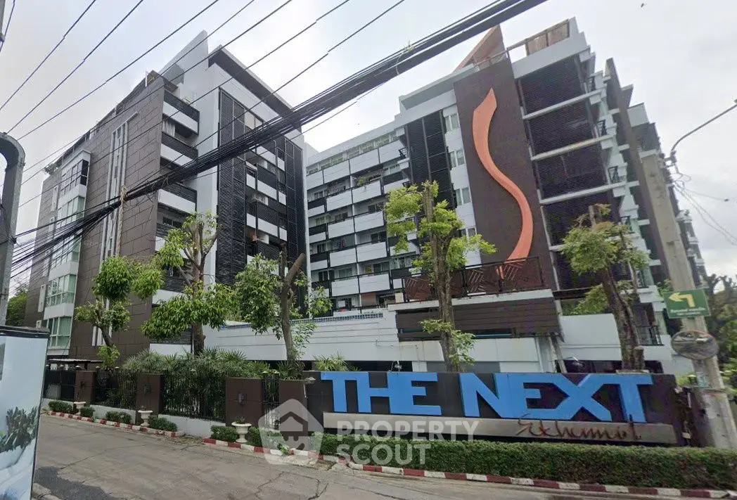 Modern condominium building with sleek design and lush greenery in urban setting.