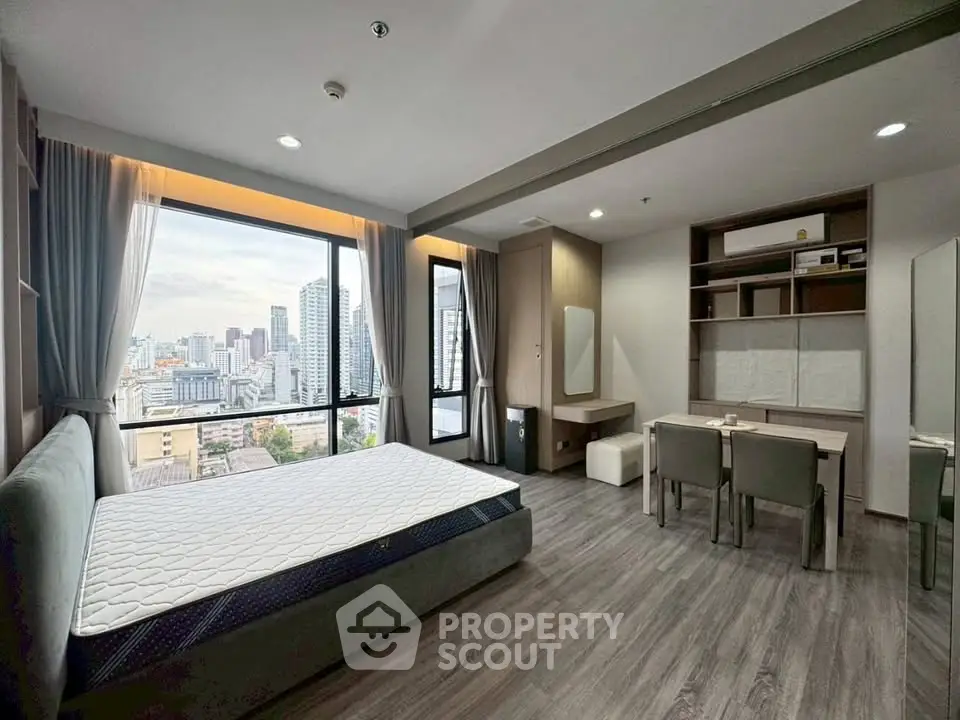 Modern bedroom with city view, featuring stylish furniture and large windows.