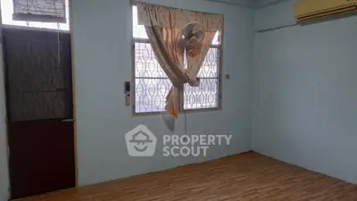 Spacious room with wooden flooring and natural light, featuring a window fan and air conditioning.