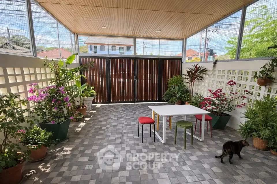 Charming outdoor patio with lush plants and modern seating, perfect for relaxation and entertaining.