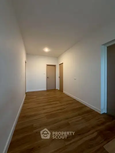 Spacious hallway with wooden flooring and modern doors in a contemporary home.
