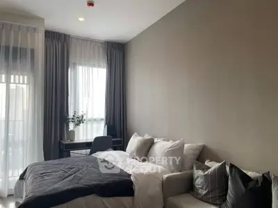 Modern bedroom with cozy bed, stylish decor, and natural light from large windows.