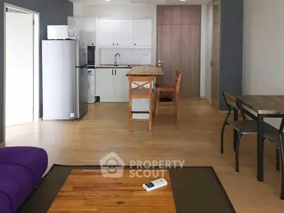 Modern open-plan kitchen and living area with wooden flooring and contemporary furniture.