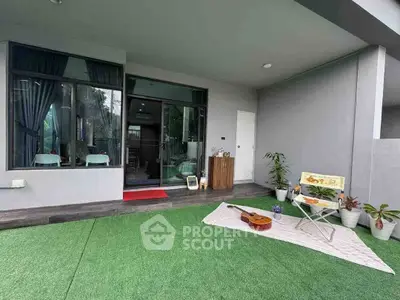 Charming outdoor patio with artificial grass and cozy seating area, perfect for relaxation.