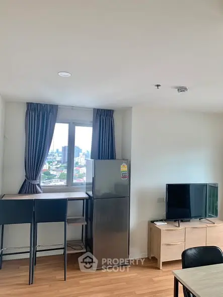 Modern apartment interior with city view, featuring a sleek fridge and TV setup.