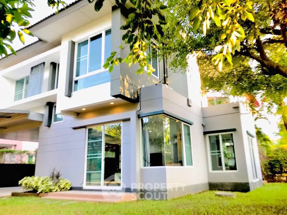 Modern two-story house with large windows and lush greenery, perfect for family living.