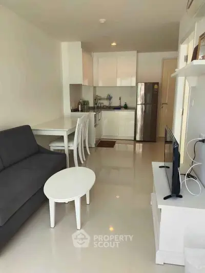 Modern open-layout living room with sleek kitchen and cozy seating area.