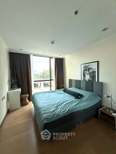 Spacious bedroom with large window and modern decor in a stylish apartment.